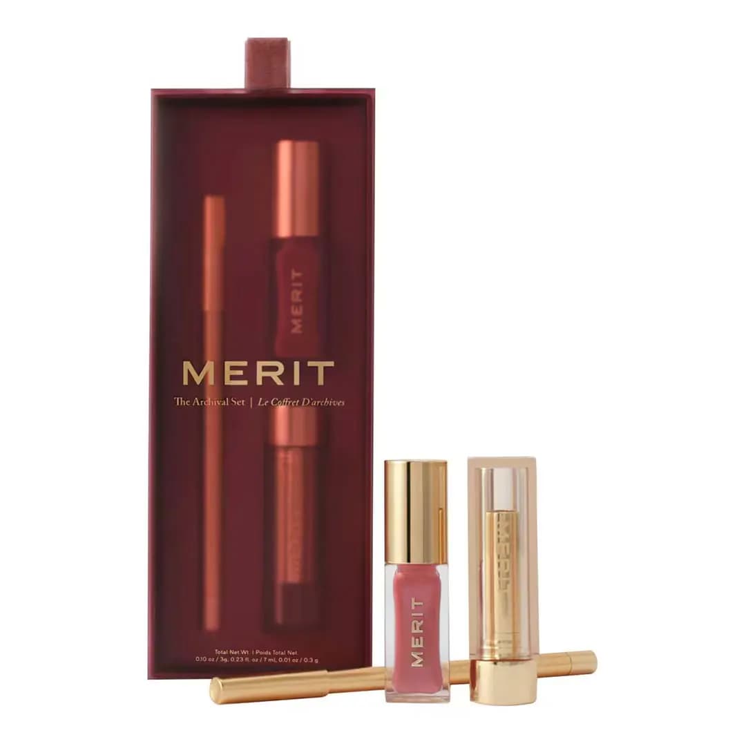 MERIT The Archival Set burgundy box beside a gold lip liner, pink tinted tube and gold lipstick with a clear cap.