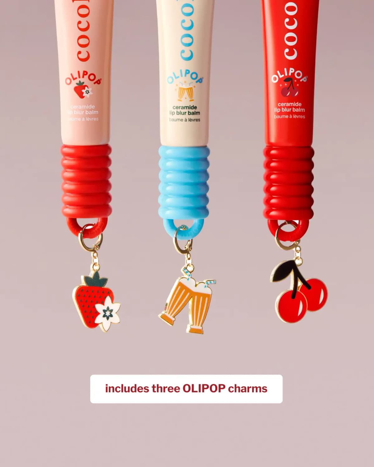 Three OLIPOP balm tubes hanging with strawberry, soda float and cherry enamel charms on a mauve background