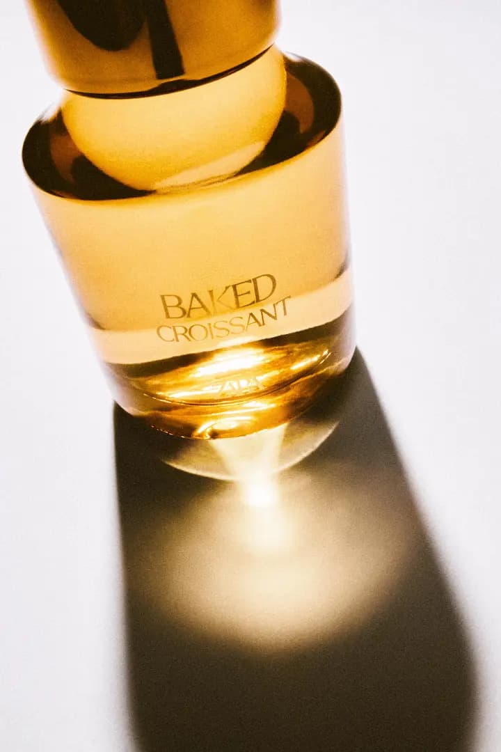 Baked Croissant bottle shot from above, sunlight glowing through the amber glass and base