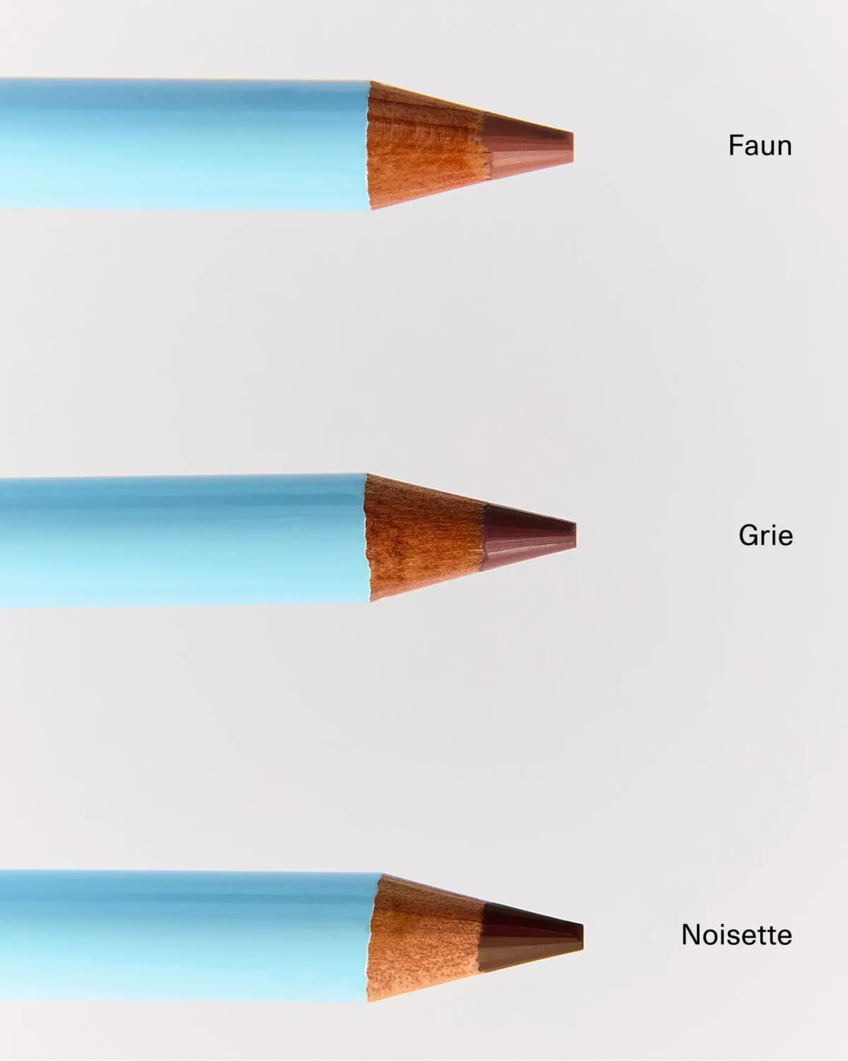 Three sharpened light-blue pencils labelled Faun, Grie and Noisette showing nude, mauve and dark brown leads