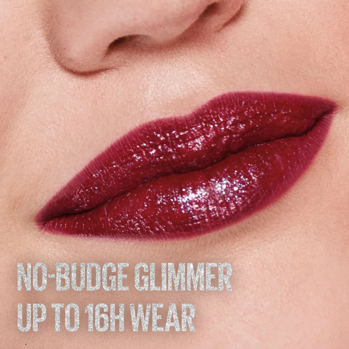 Close-up of deep berry lips with a sparkling glimmer finish, captioned no-budge glimmer, up to 16H wear