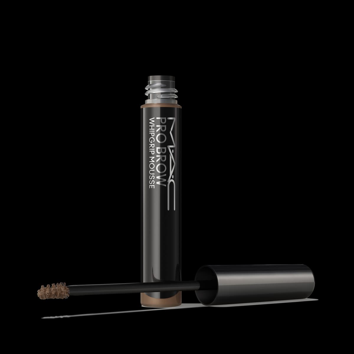 Black MAC Pro Brow WhipGrip Mousse tube standing upright with cap and spoolie wand beside it