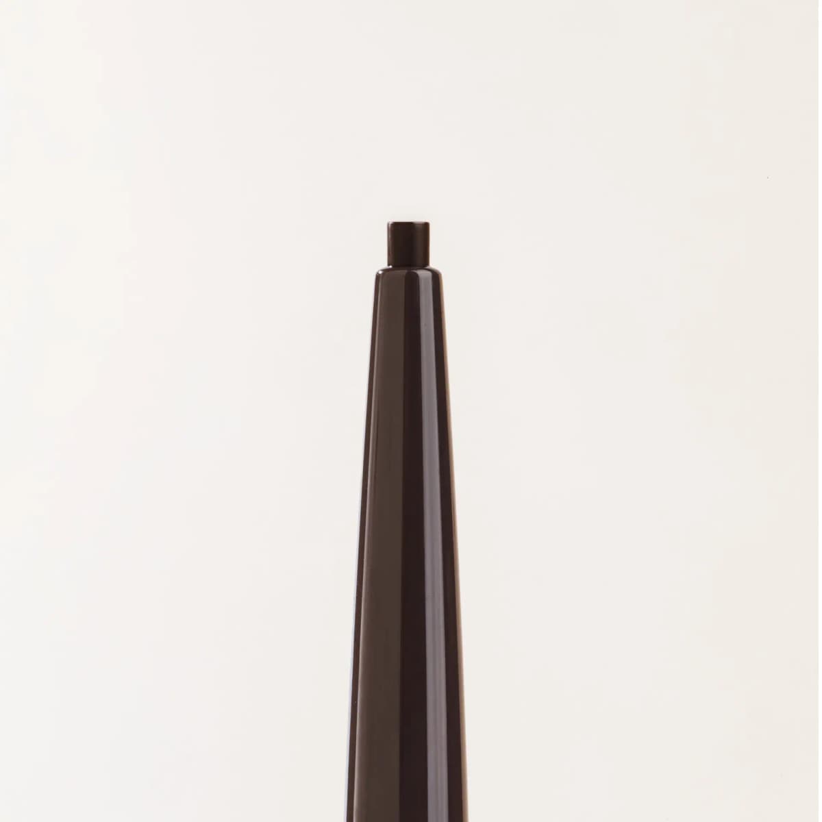 Close-up of the Truffle pencil's fine brown tip emerging from a glossy tapered brown casing.