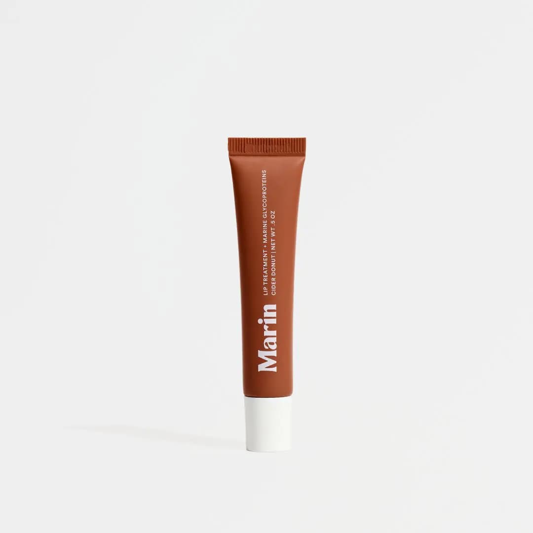 Rust-brown Marin Cider Donut Lip Treatment tube with a white cap, standing upright against a plain white background