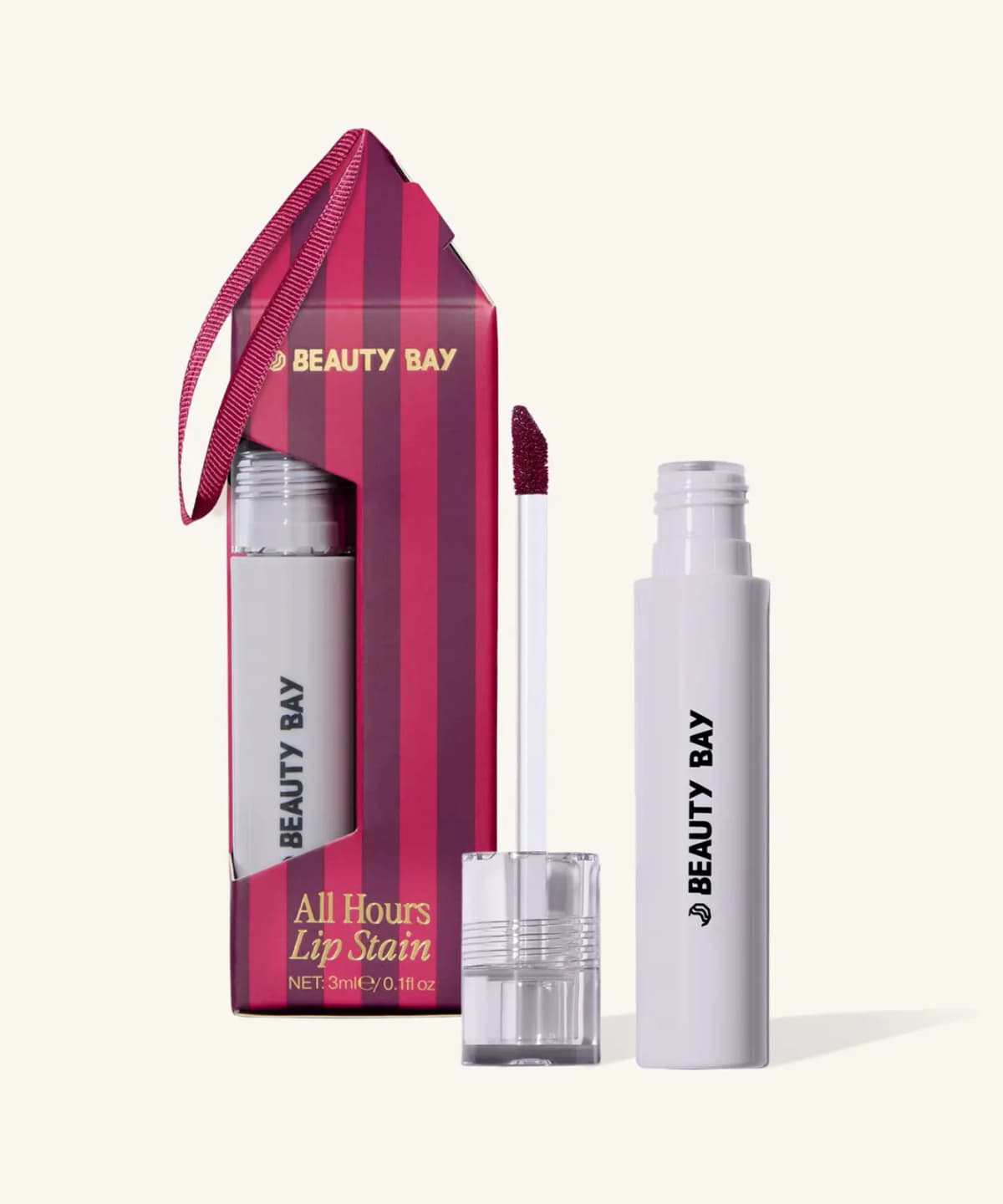 All Hours Lip Stain in lilac tube with berry doe-foot applicator beside its striped ornament-style box with ribbon