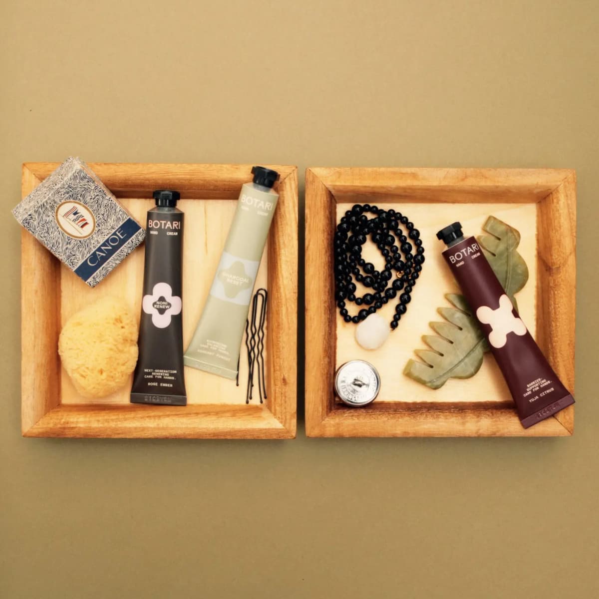 BOTARI Noni Renew and Charcoal Reset minis in a wooden tray beside Cica Protect in another, with beads and a jade comb