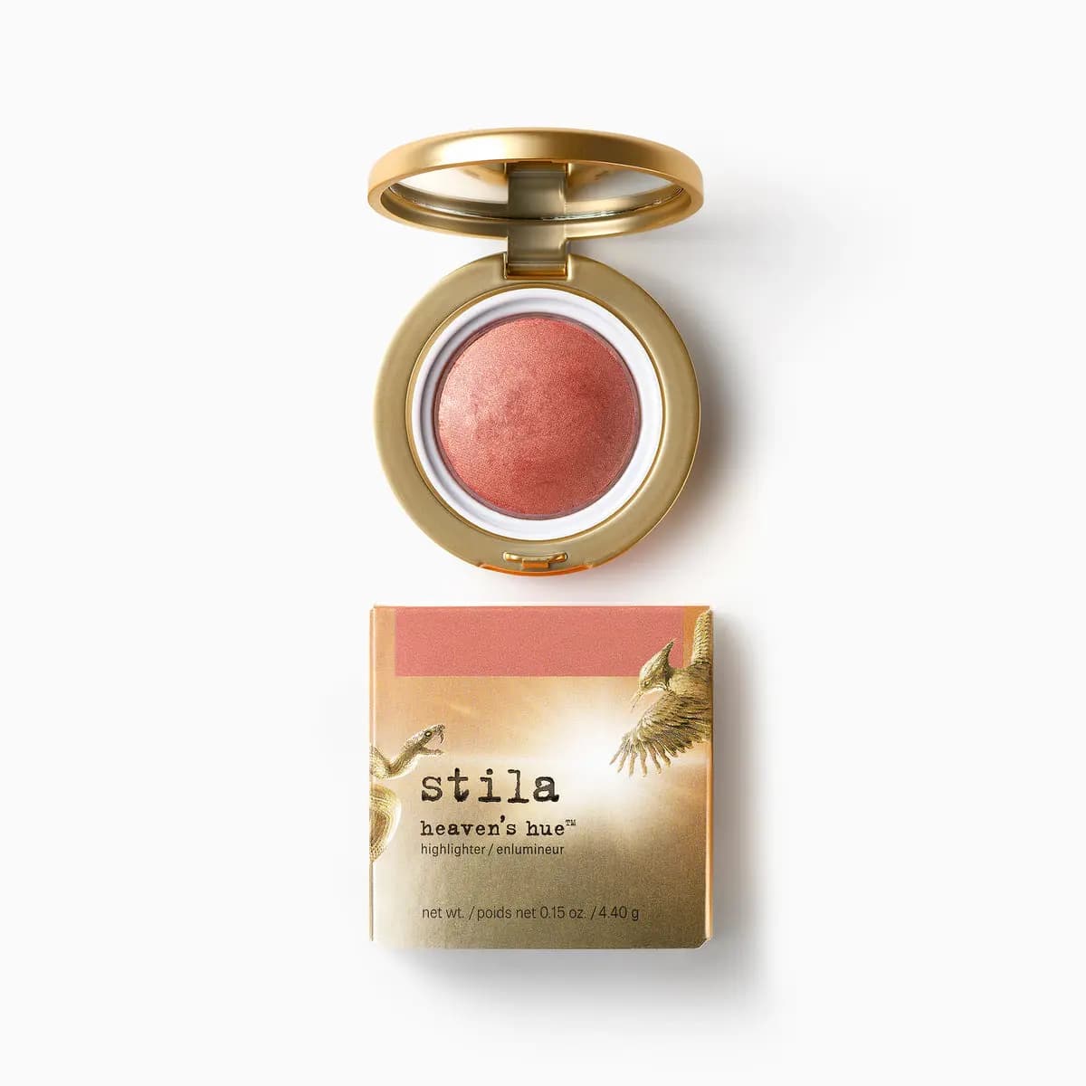Heaven's hue highlighter, a rosy peach baked powder in an open gold mirrored compact, above its gold box
