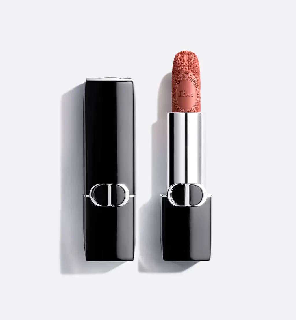 Black Dior lipstick case with CD logo beside a peach-coral bullet engraved with a medallion and Cannage pattern