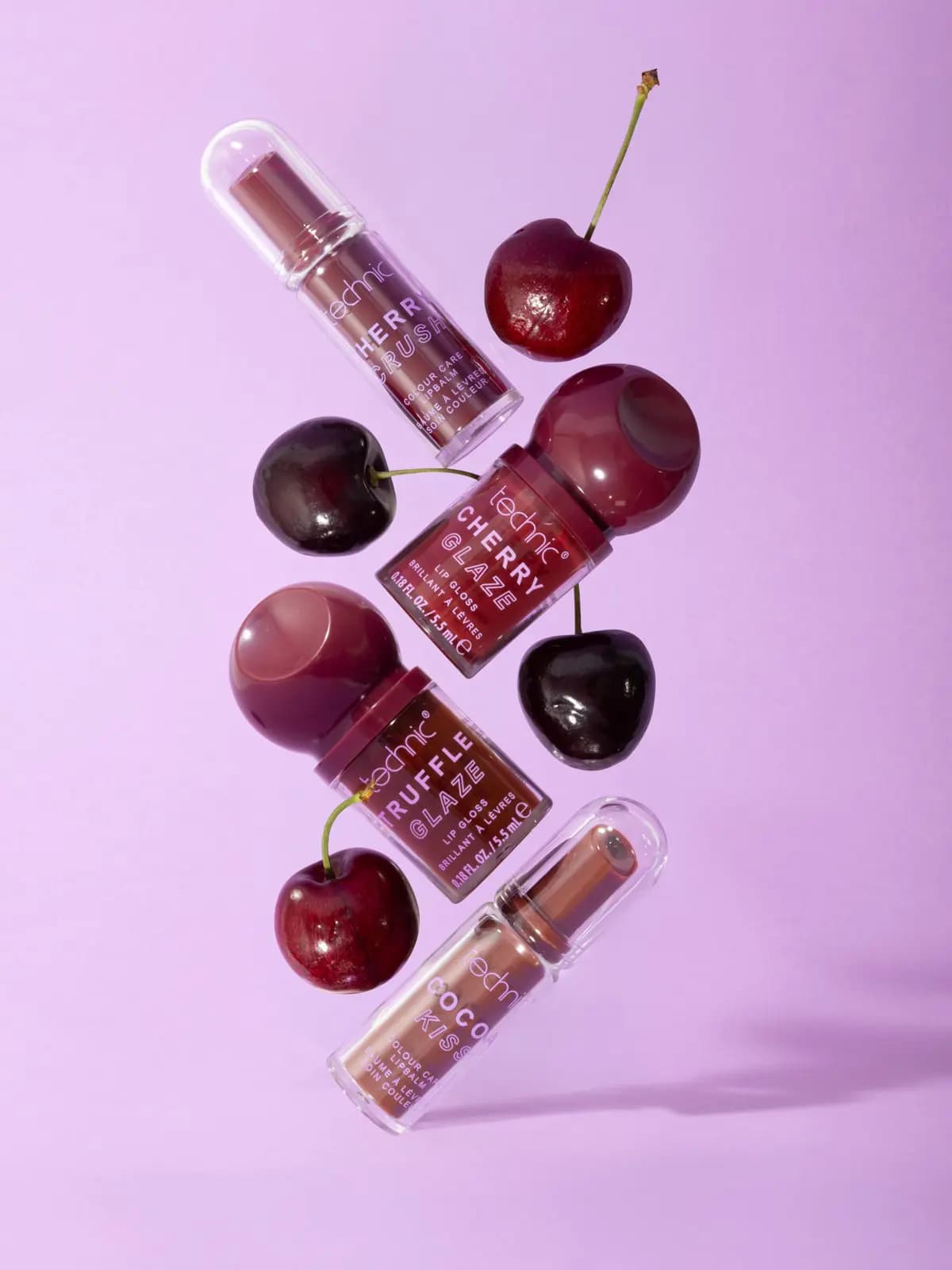 Cherry Crush, Cherry Glaze, Truffle Glaze and Cocoa Kiss lip products floating with cherries against lilac
