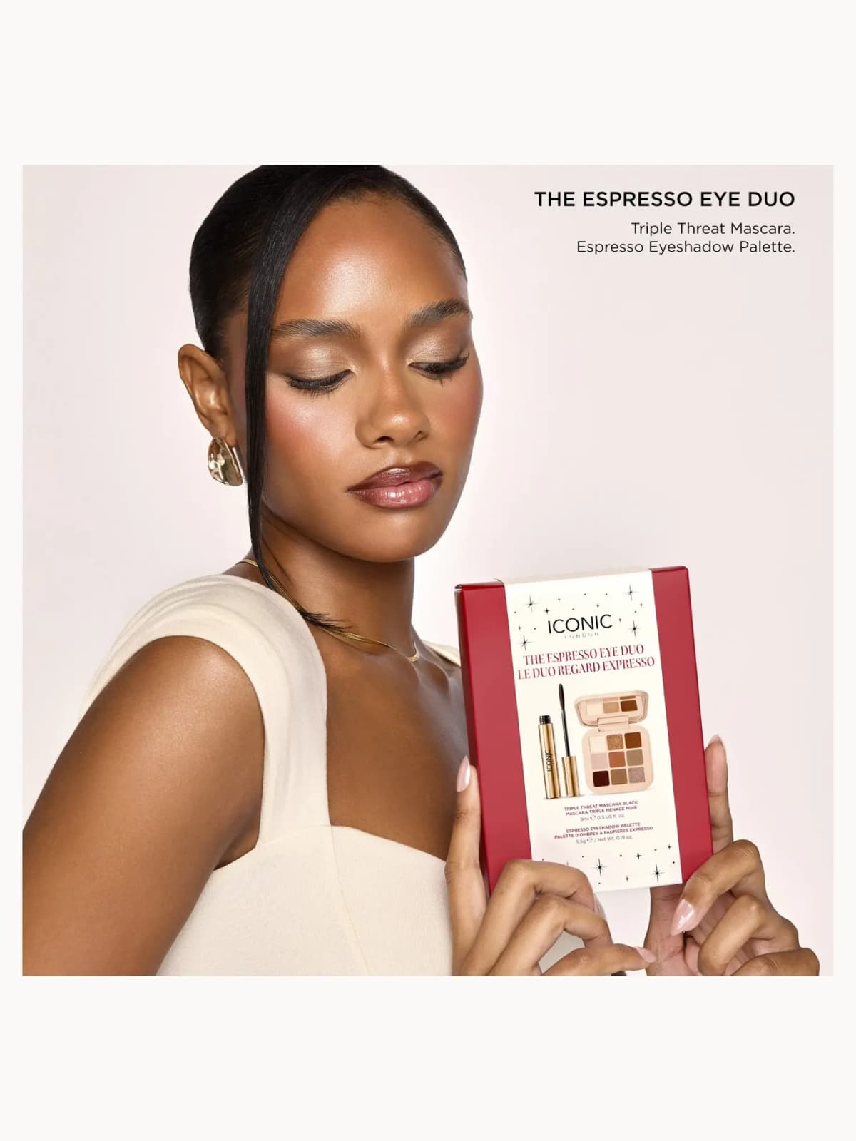 Model with dewy skin and glossy lips holding the red Espresso Eye Duo box, with set contents listed above