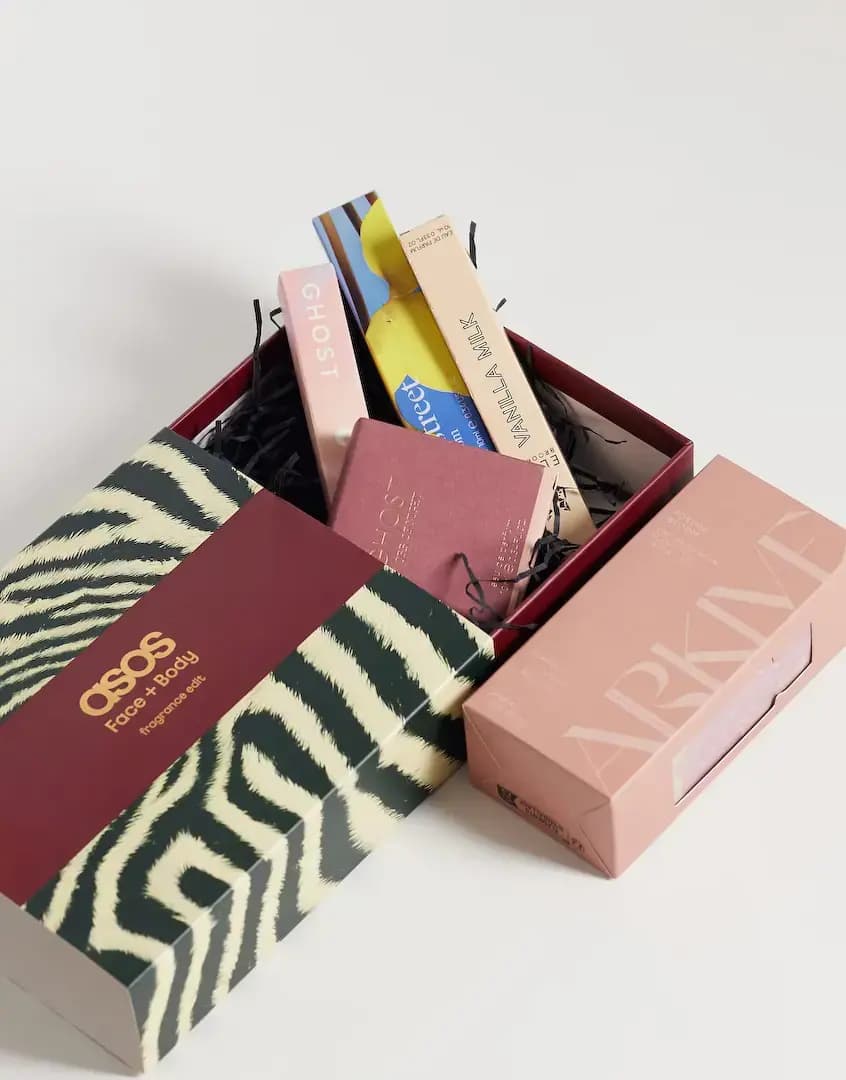Open zebra-print box holding boxed Ghost, Floral Street and Vanilla Milk sprays beside a pink ARKIVE carton