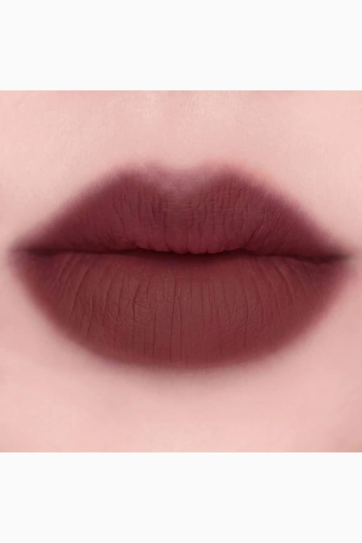 Close-up of lips wearing a deep matte burgundy-brown lipstick shade on fair skin