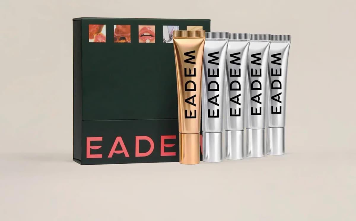 Dark green EADEM box beside one gold and four silver Le Chouchou lip balm tubes on a beige backdrop