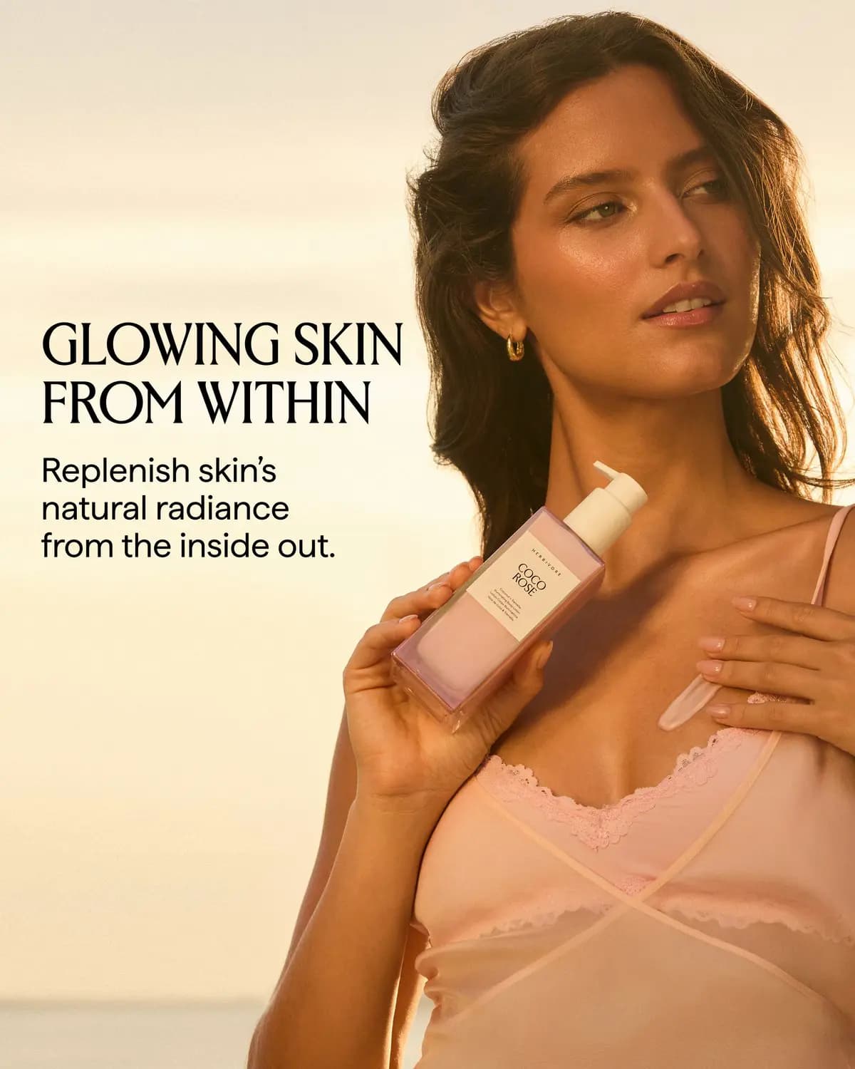 Model in a pink lace slip holds a COCO ROSE bottle with a lotion streak across the chest; text reads Glowing Skin From Within