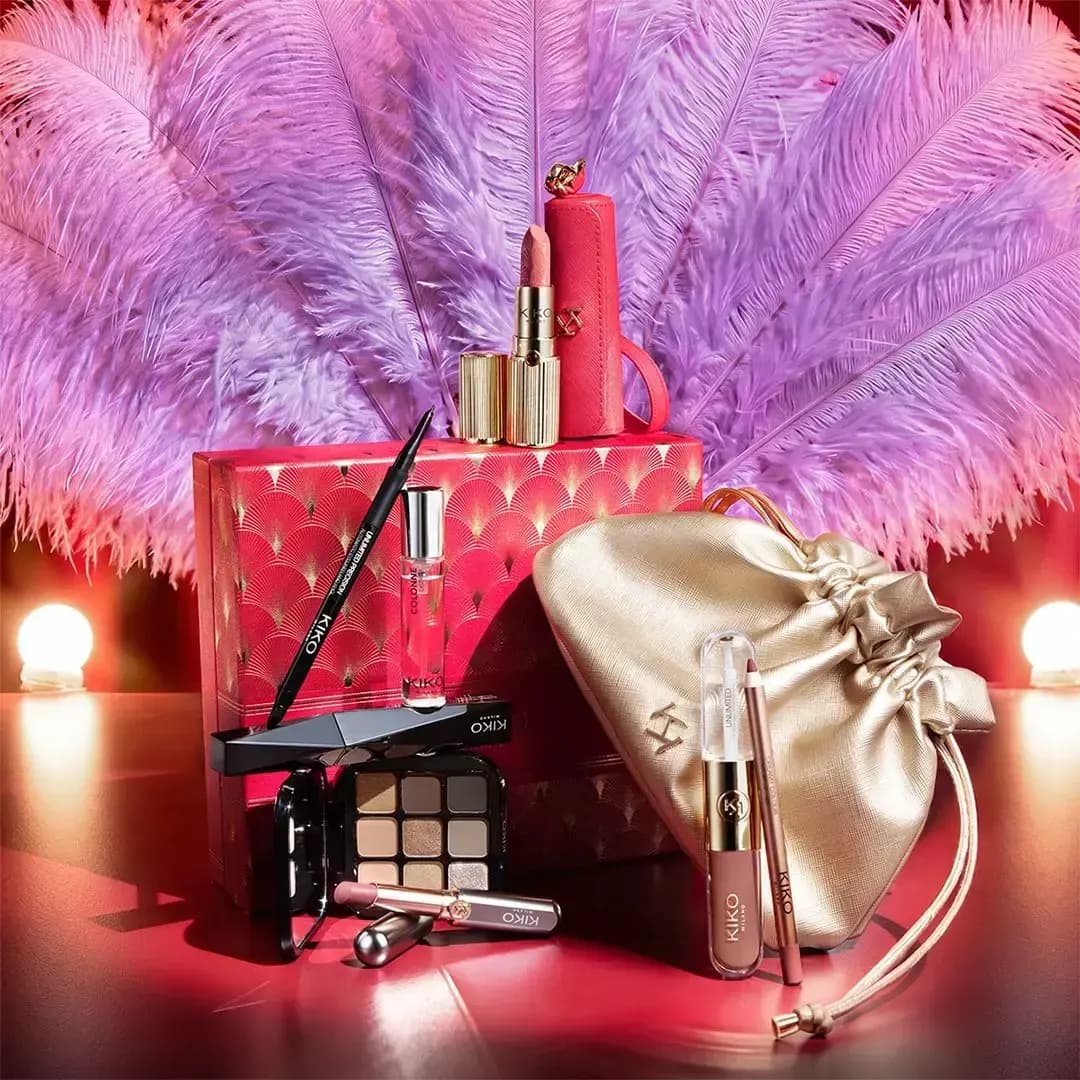 KIKO Milano holiday sets with eyeshadow palette, lipsticks and red lipstick case before pink ostrich feathers