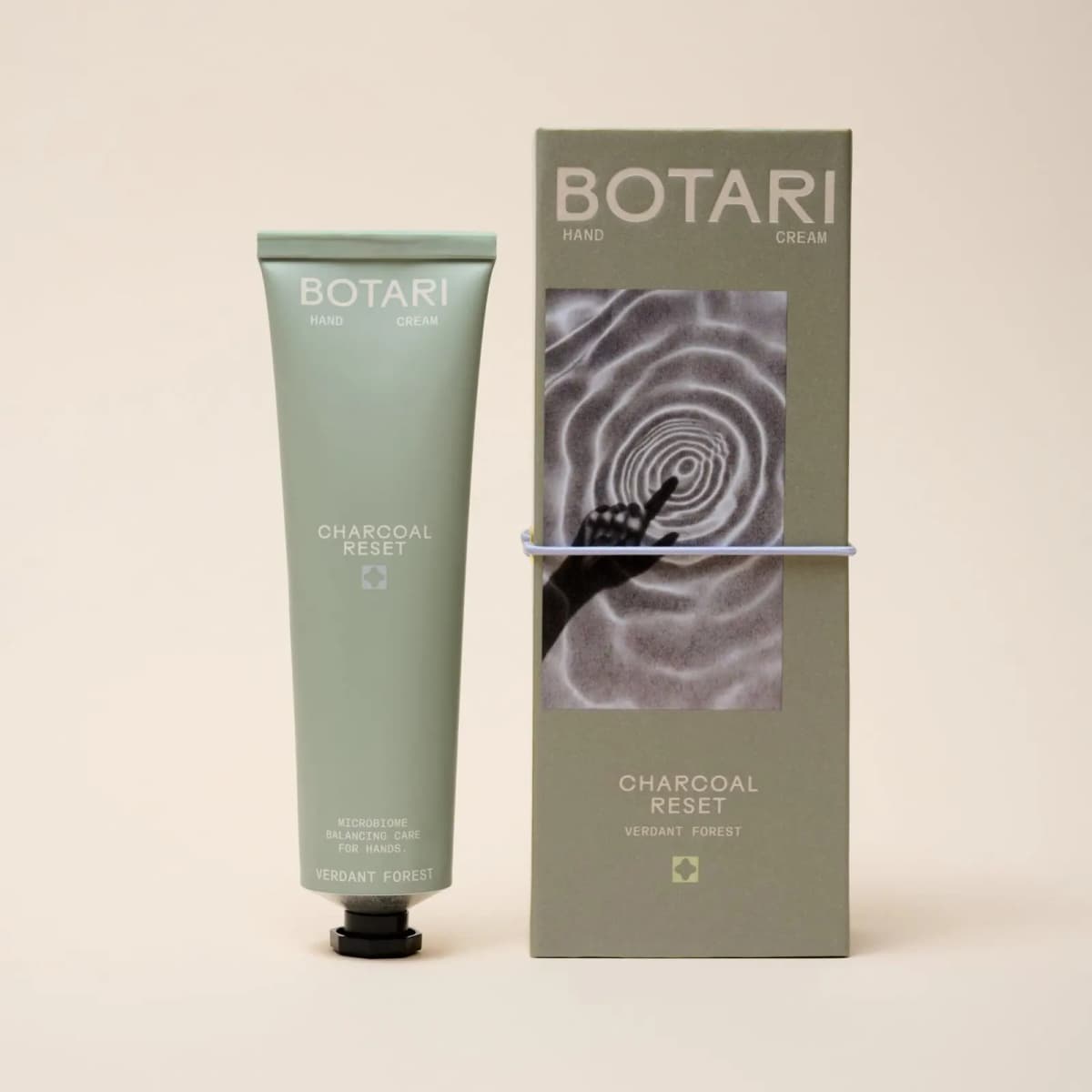 Sage green BOTARI Charcoal Reset Verdant Forest tube next to its box printed with a hand touching rippling water
