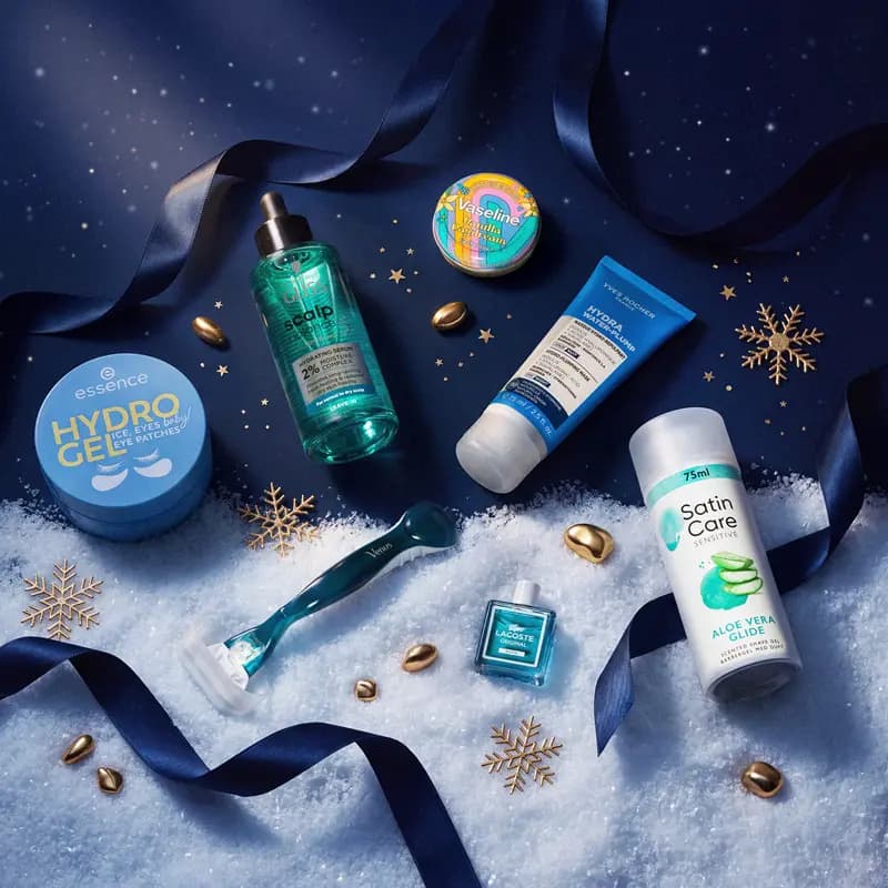 Blue-toned beauty products on snow including essence Hydro Gel patches, Vaseline, Venus razor and Satin Care shave gel