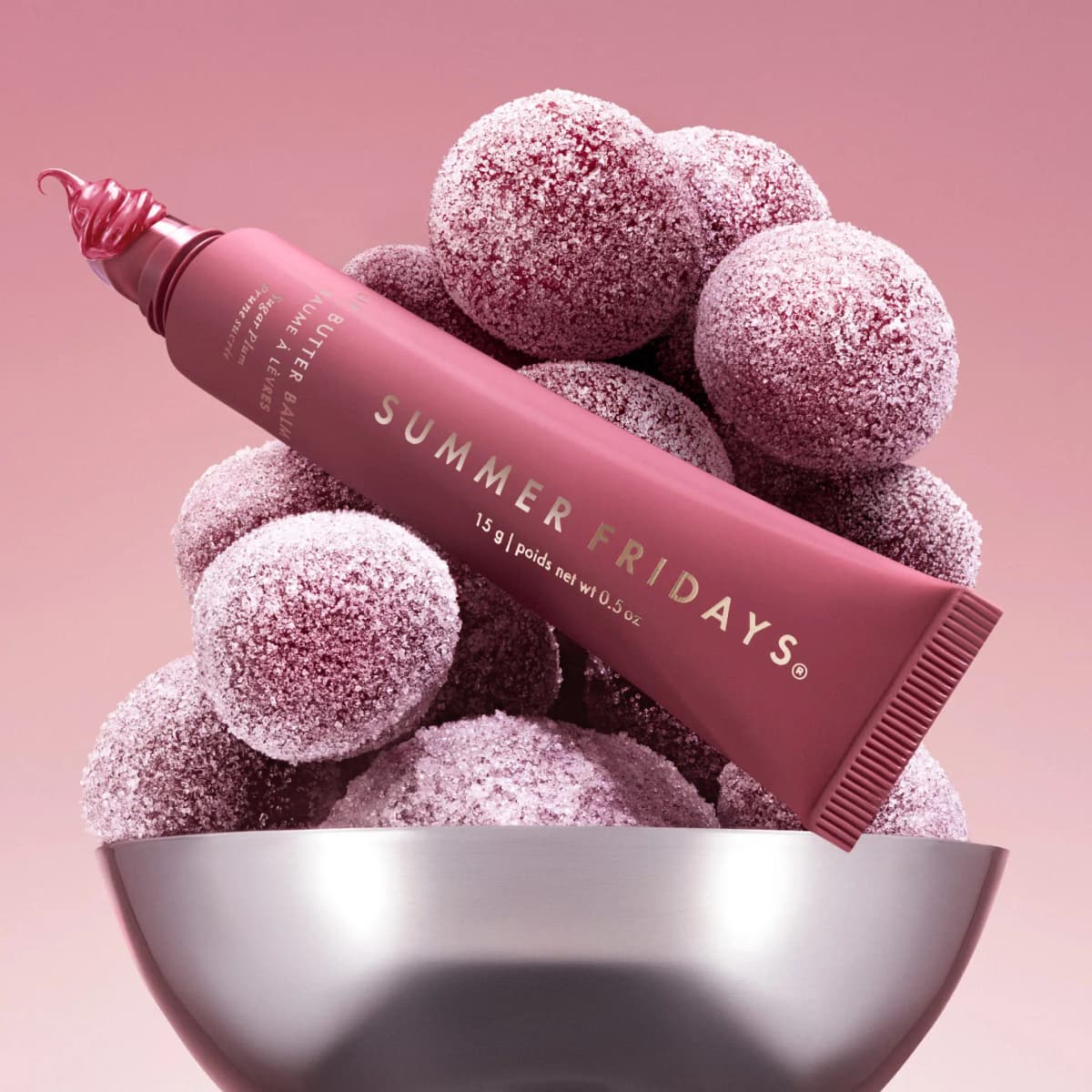 Sugar Plum Lip Butter Balm dispensing a glossy swirl, resting on sugar-coated plums in a silver bowl