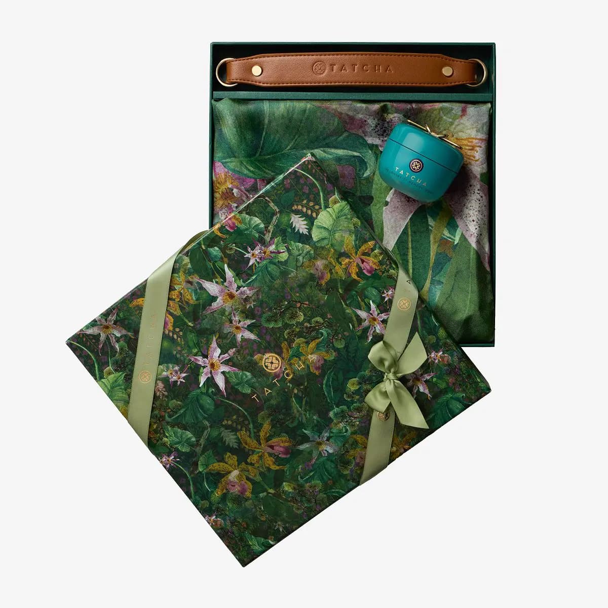Green floral Tatcha box tied with ribbon, opened to a leather strap, jungle-print cloth and a teal Tatcha cream jar