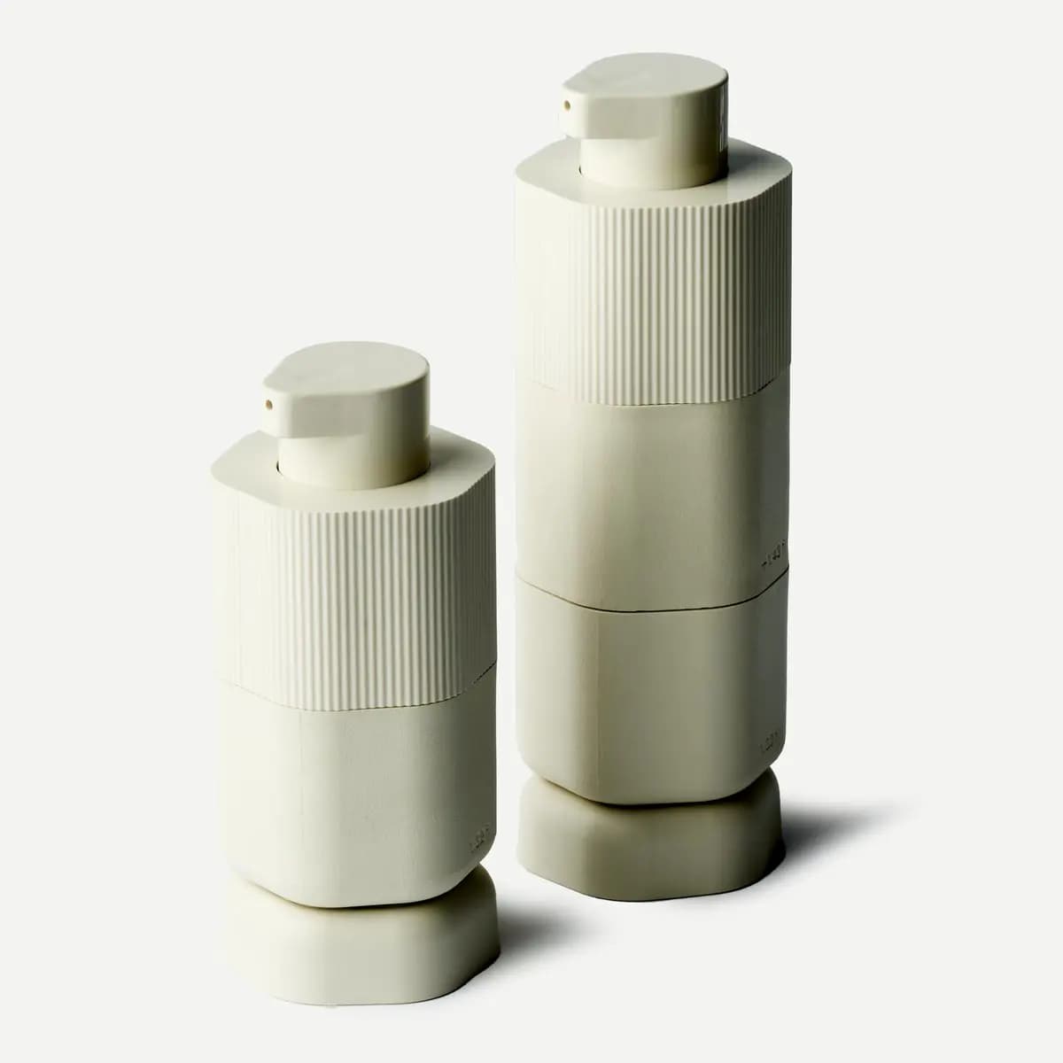 Medium and Large cream Pump Capsules with ribbed tops standing on hexagonal bases, side by side