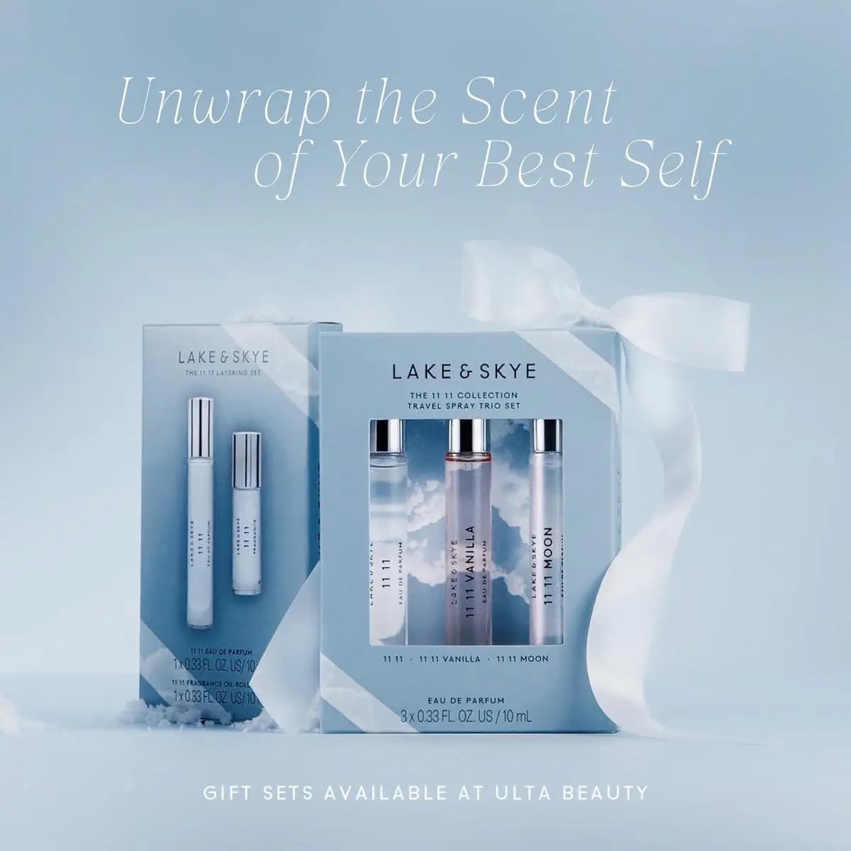 Two Lake & Skye gift sets with white ribbon on a pale blue snowy backdrop, text reads Unwrap the Scent of Your Best Self.