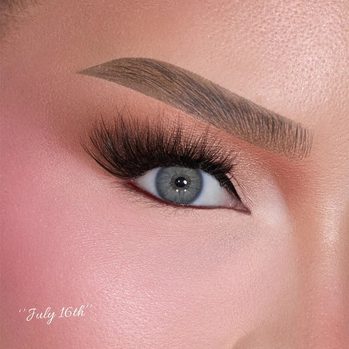 Close-up of a blue eye wearing full dramatic voluminous lashes with peach shadow, labeled 'July 16th'.