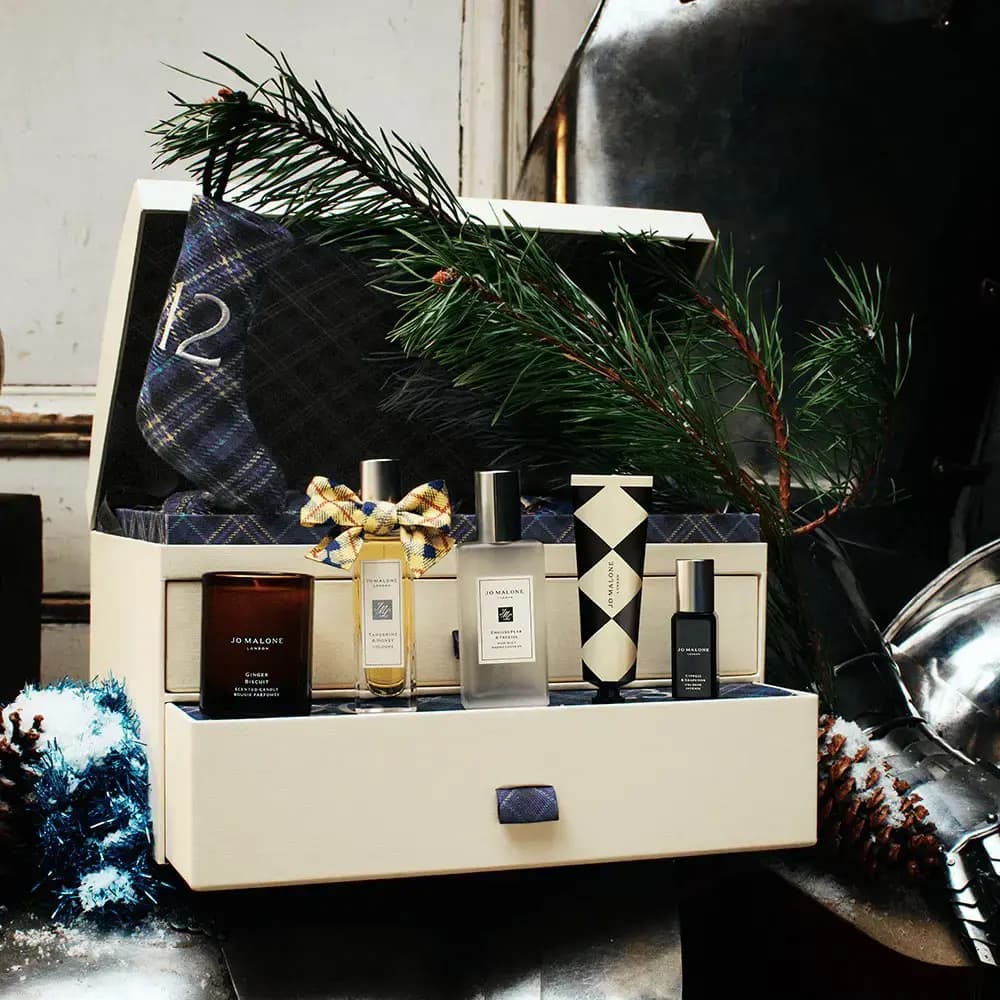 Cream advent chest with tartan stocking, pine branch, Ginger Biscuit candle and minis in a wintry scene