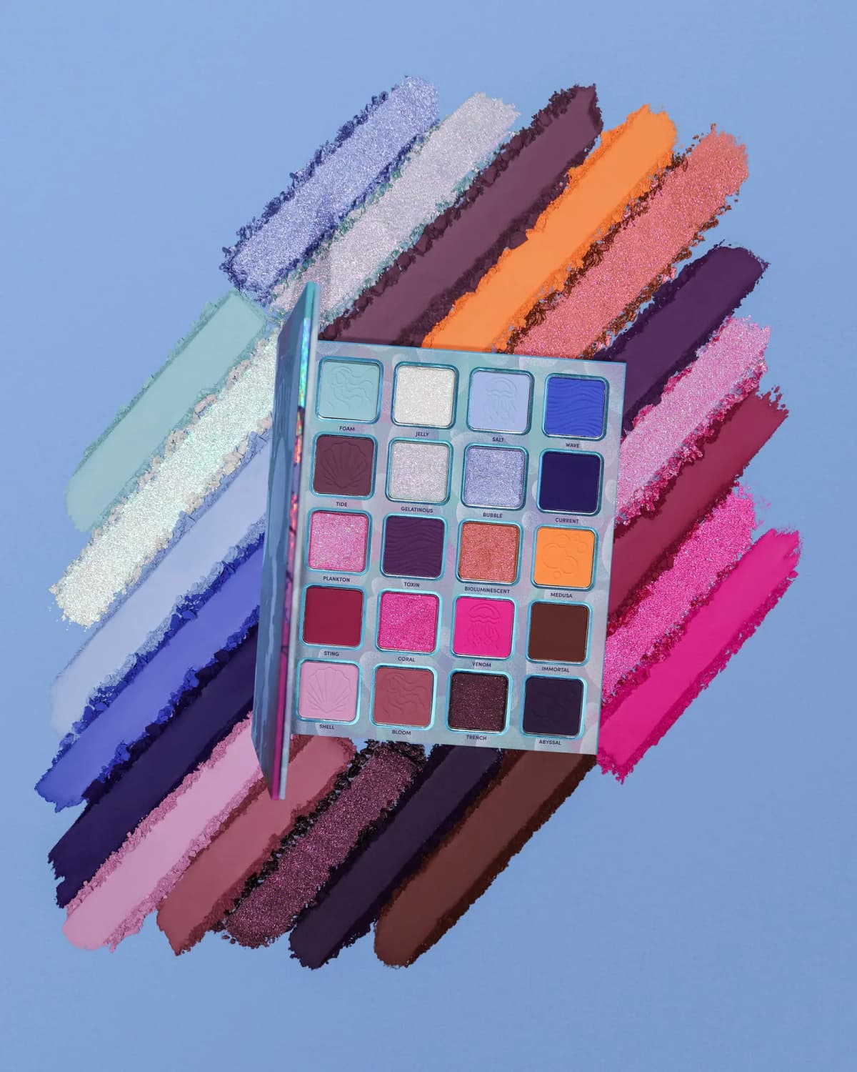 Open eyeshadow palette centered on a fan of powder swatches in blue, purple, orange, pink, and berry tones