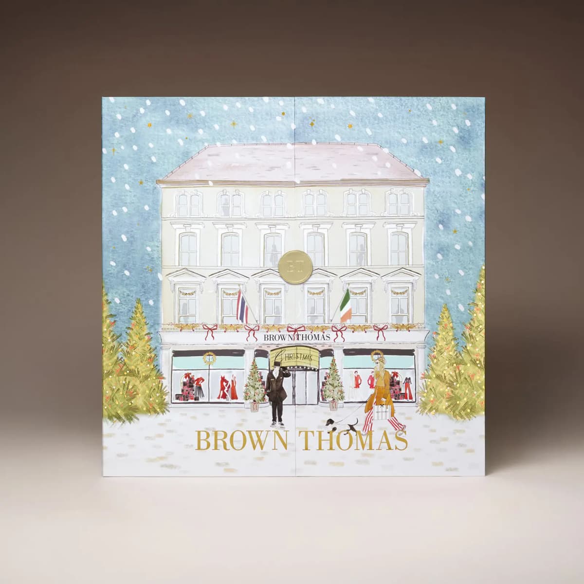Closed square advent calendar illustrated with the Brown Thomas storefront, Christmas trees and snowfall against a blue sky.