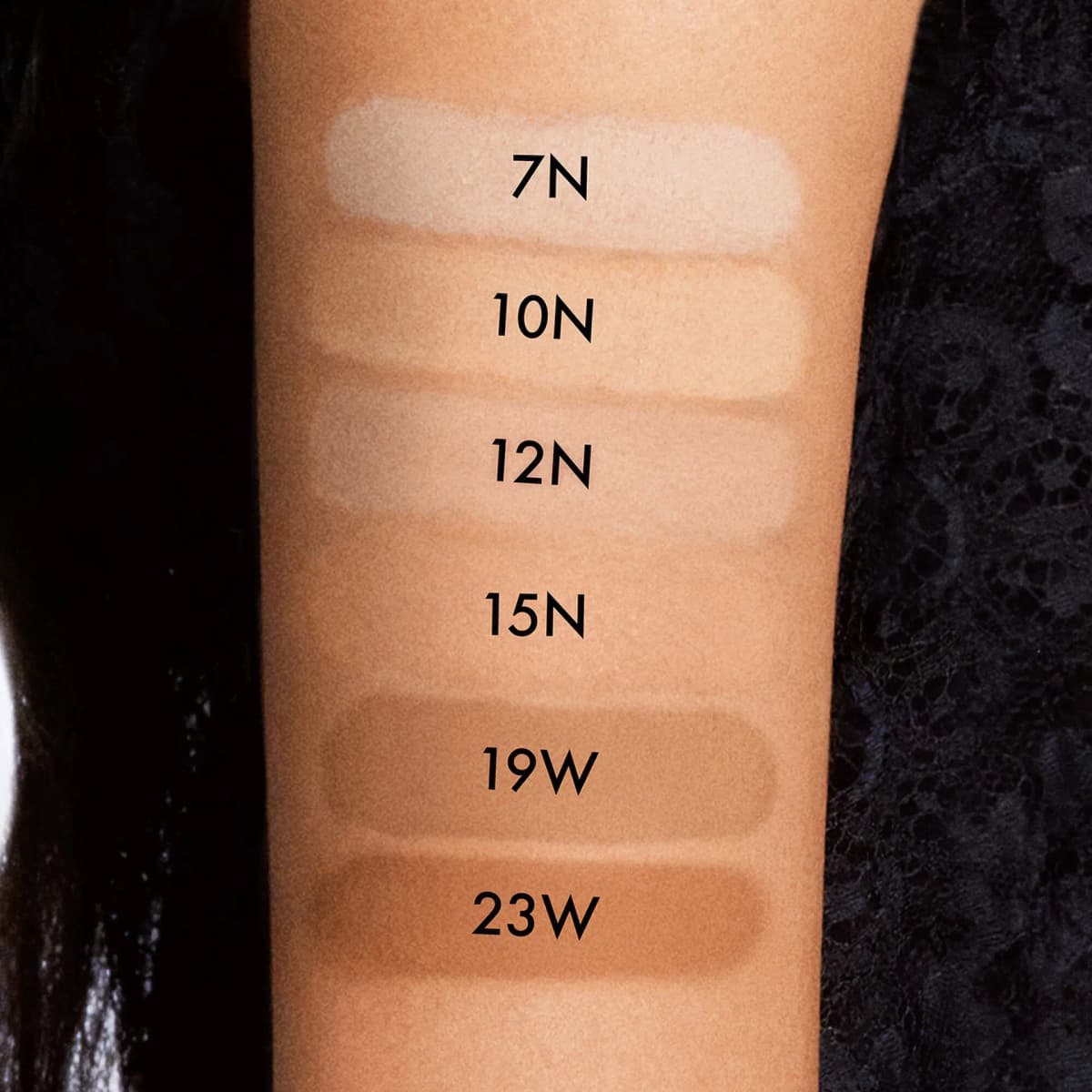 Six powder swatches on a forearm labelled 7N, 10N, 12N, 15N, 19W and 23W, ranging from fair to warm tan