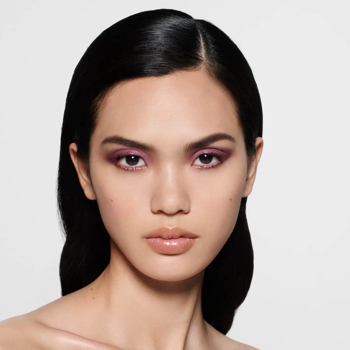 Model with sleek black hair wearing mauve-pink eyeshadow and sparkling pink liner on the lower lash line