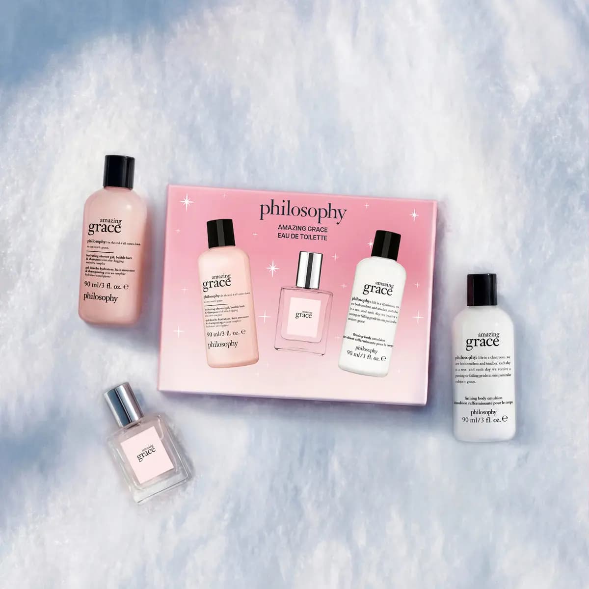 Pink philosophy amazing grace eau de toilette set with shower gel, mini perfume and body emulsion arranged on snow