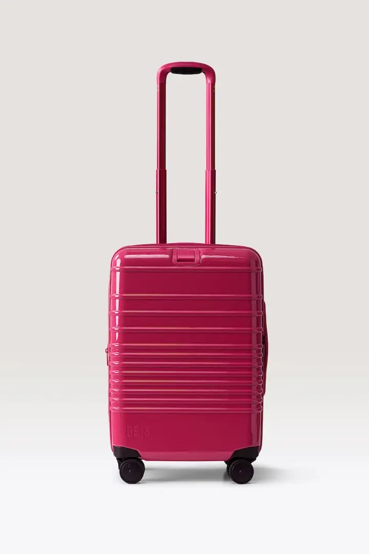 Glossy raspberry BÉIS carry-on hard-shell spinner with ridged front and extended pink handle