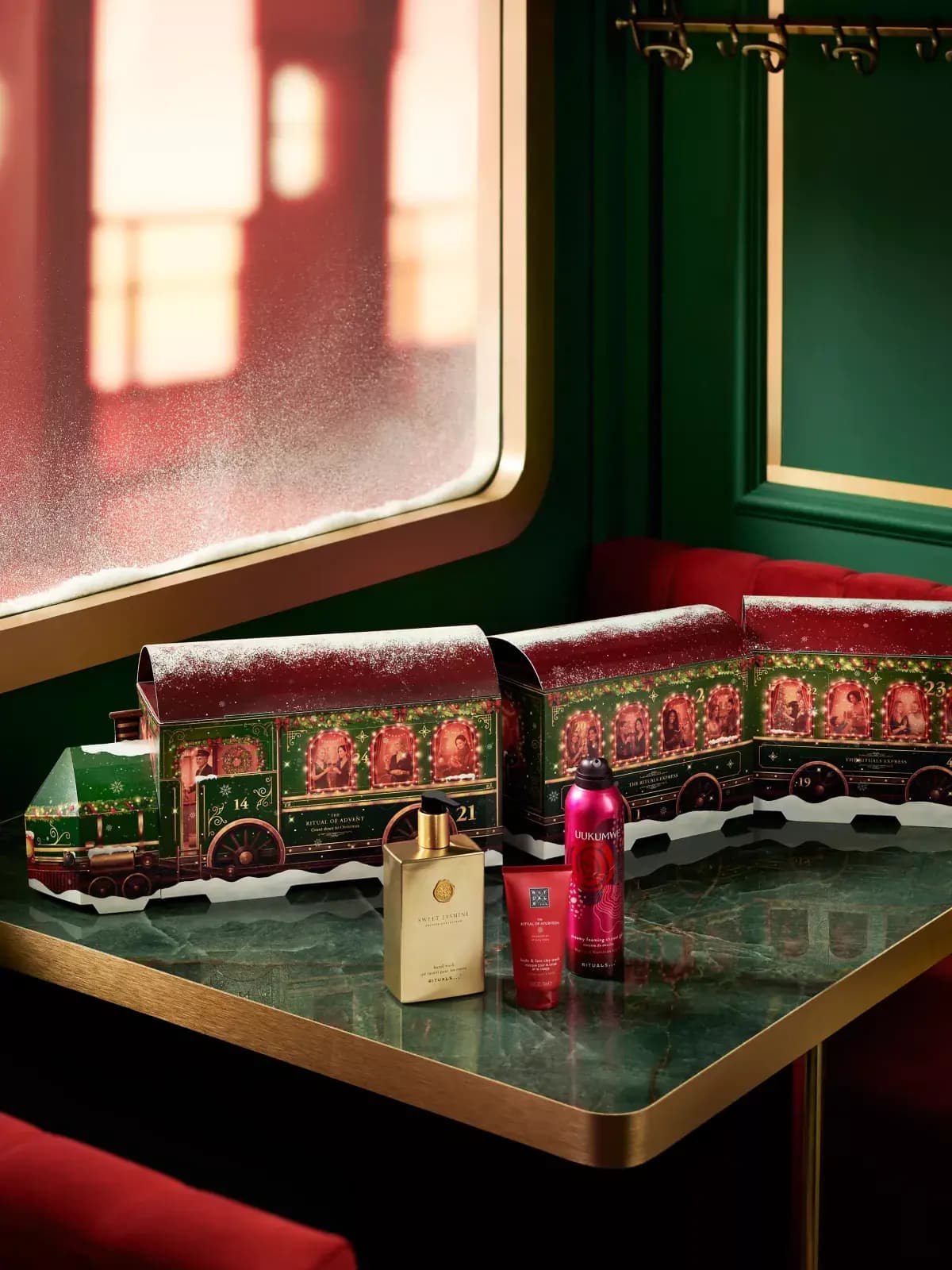 Train advent calendar on a green marble table with Sweet Jasmine hand wash, Ayurveda clay mask and Uukumwe shower foam