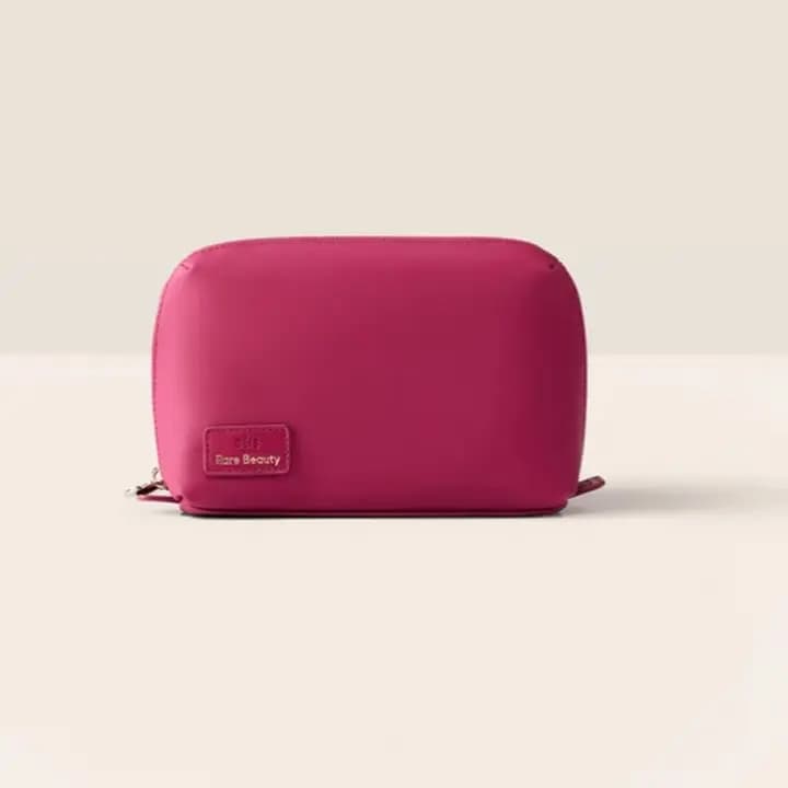 Small raspberry nylon cosmetic pouch with a Rare Beauty logo patch and gold zipper pull