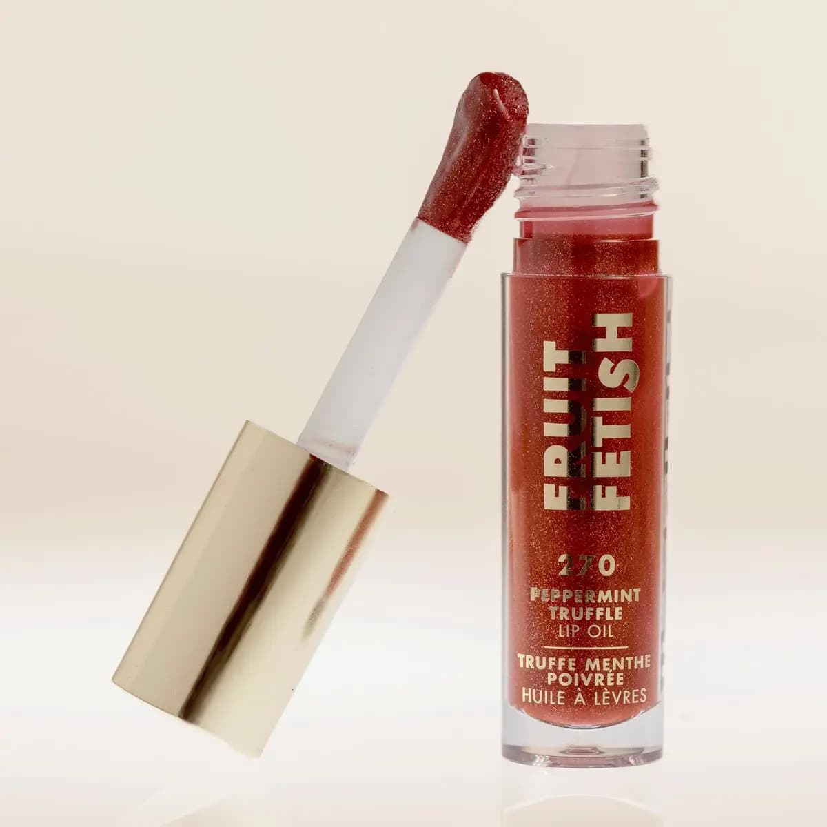 Peppermint Truffle tube on a cream backdrop with its glossy red applicator leaning against the rim