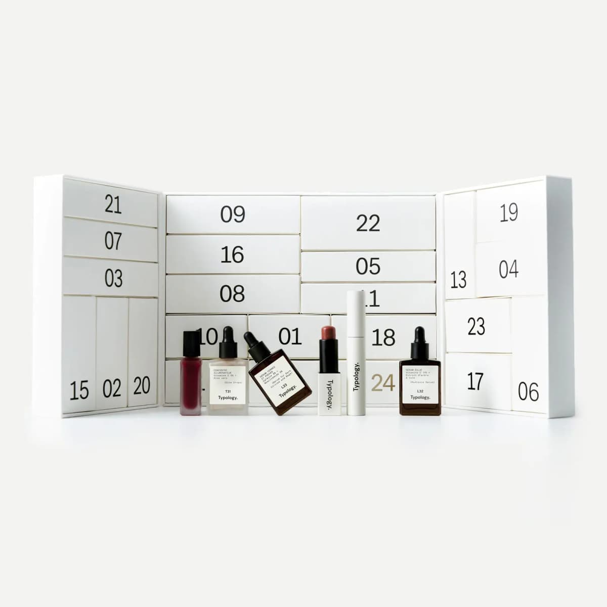 Typology Advent Calendar opened to show numbered white drawers, with serums, a lip balm and a tube displayed in front.