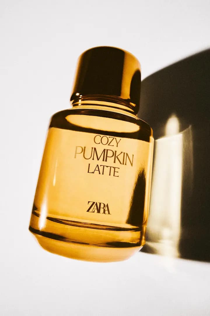 Cozy Pumpkin Latte bottle tilted against a white backdrop with a gold cap and dark shadow