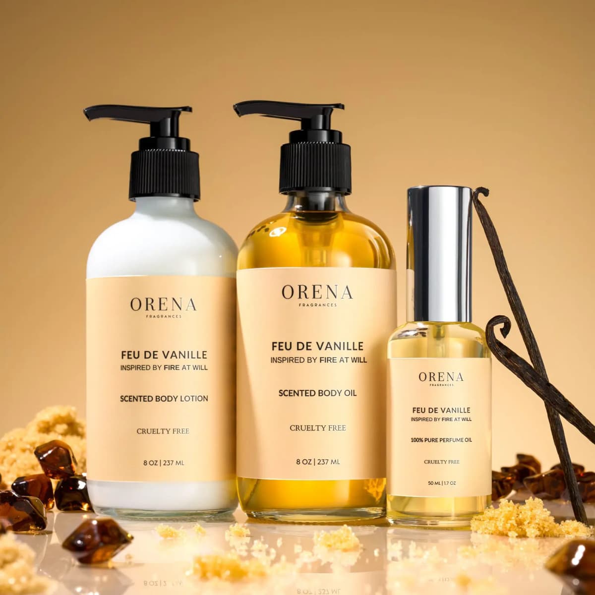 Feu de Vanille lotion, body oil and perfume oil with peach labels, vanilla pods, brown sugar and amber on a golden backdrop