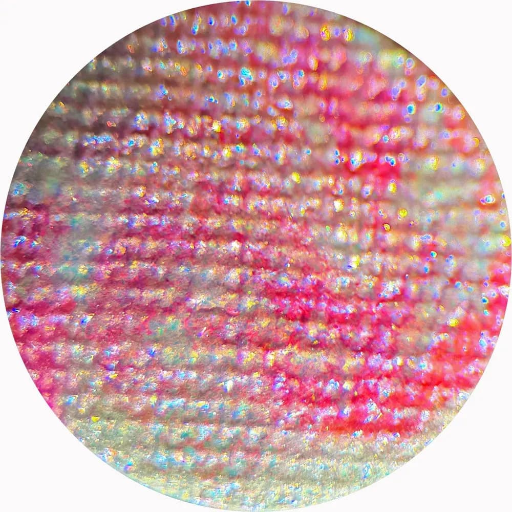 Macro circle of a pink and red eyeshadow with blue, gold and violet glitter sparkle