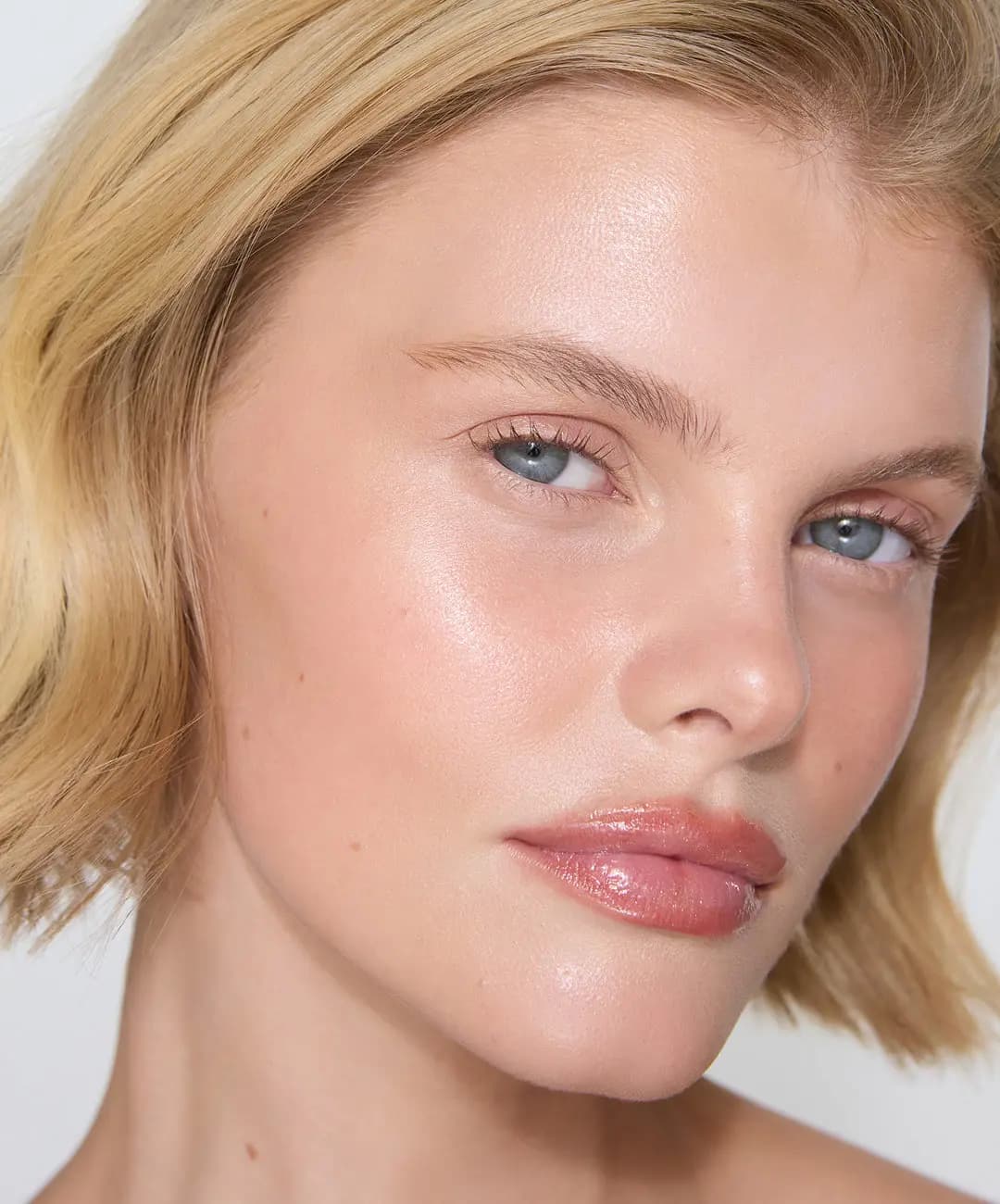 Blonde model with glowing cheekbones, groomed brows and glossy pink-nude lips