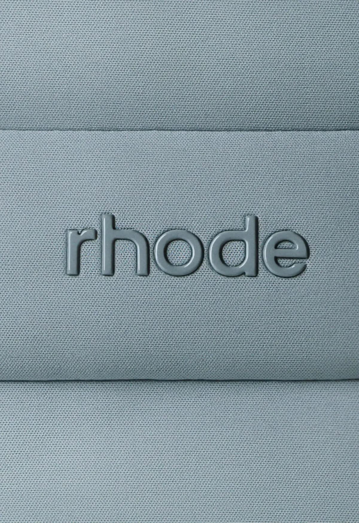Macro view of glossy raised rhode logo on fine blue-grey woven neoprene fabric