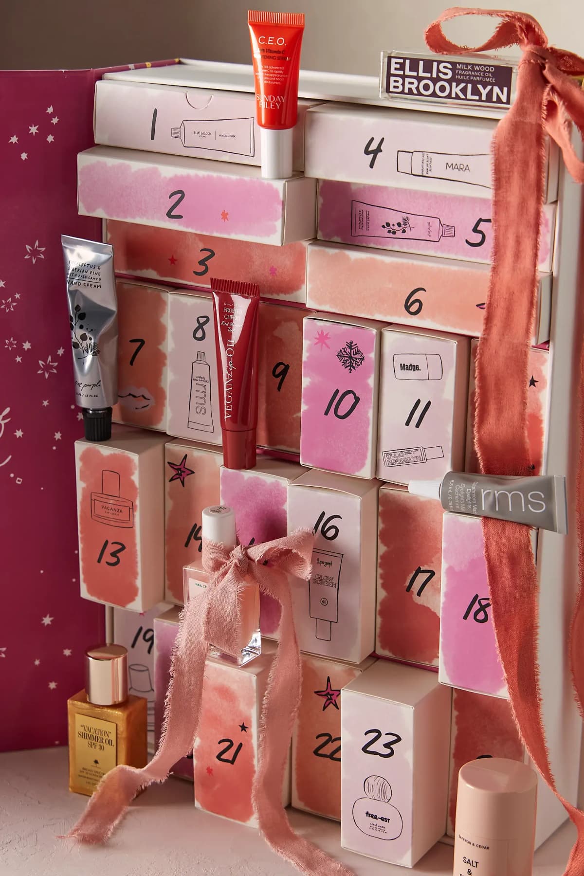 Angled view of open calendar with pulled-out drawers, Manucurist nail polish tied with dusty pink ribbon and coral bow