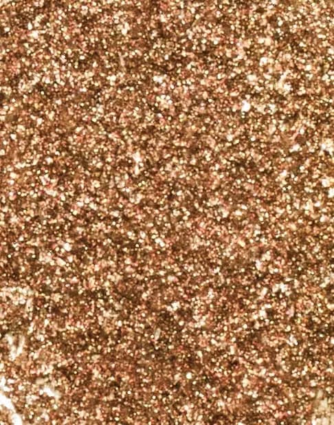 Macro texture of glittering bronze-gold shimmer pigment with flecks of pink and gold pearl.