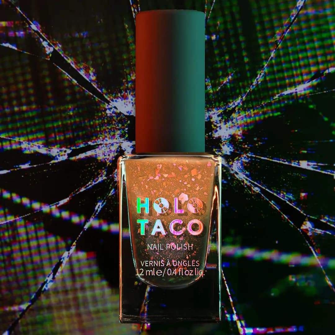 Bottle of orange jelly polish with pink and copper flakes against a shattered screen backdrop