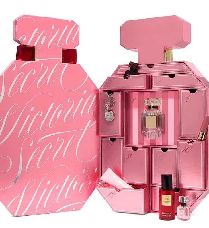 Open book-style Bombshell calendar revealing 12 numbered pink drawers with perfume, mist, and charm inside.