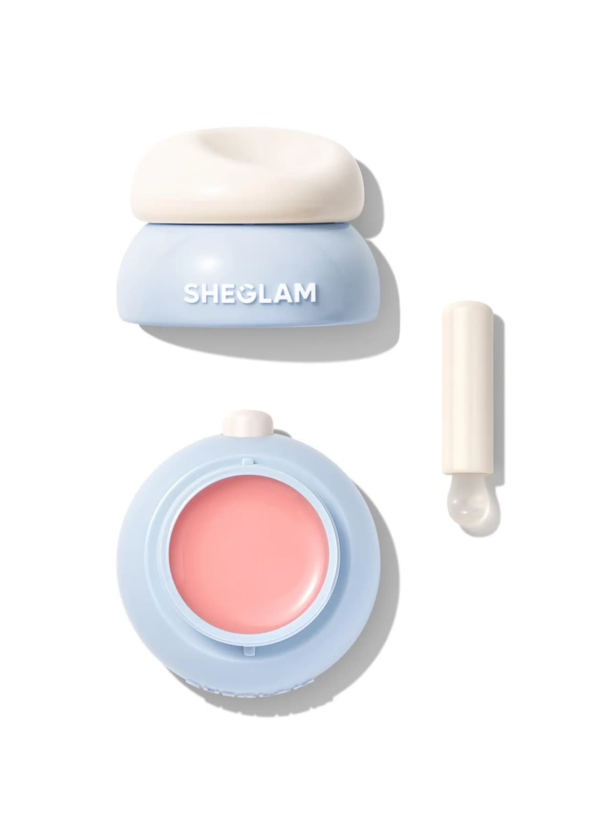 Blue jar with cream lid, open pan of pink jelly lip mask and white silicone-tipped applicator on white