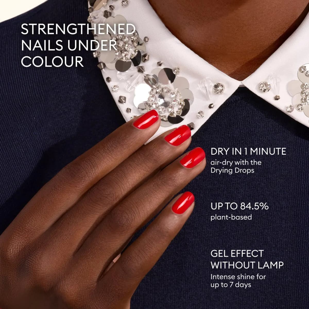 Close-up of hand with glossy red manicure against embellished collar, listing quick-dry and plant-based benefits