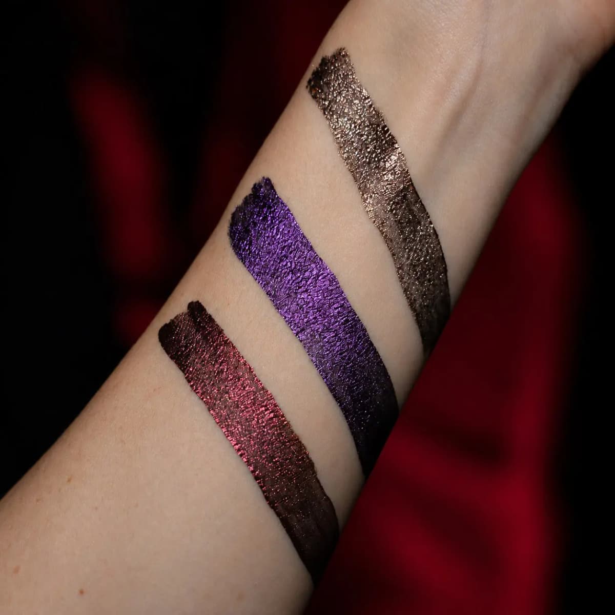 Arm swatches of the three liquid eyeshadows in metallic burgundy, violet and bronze foil finishes