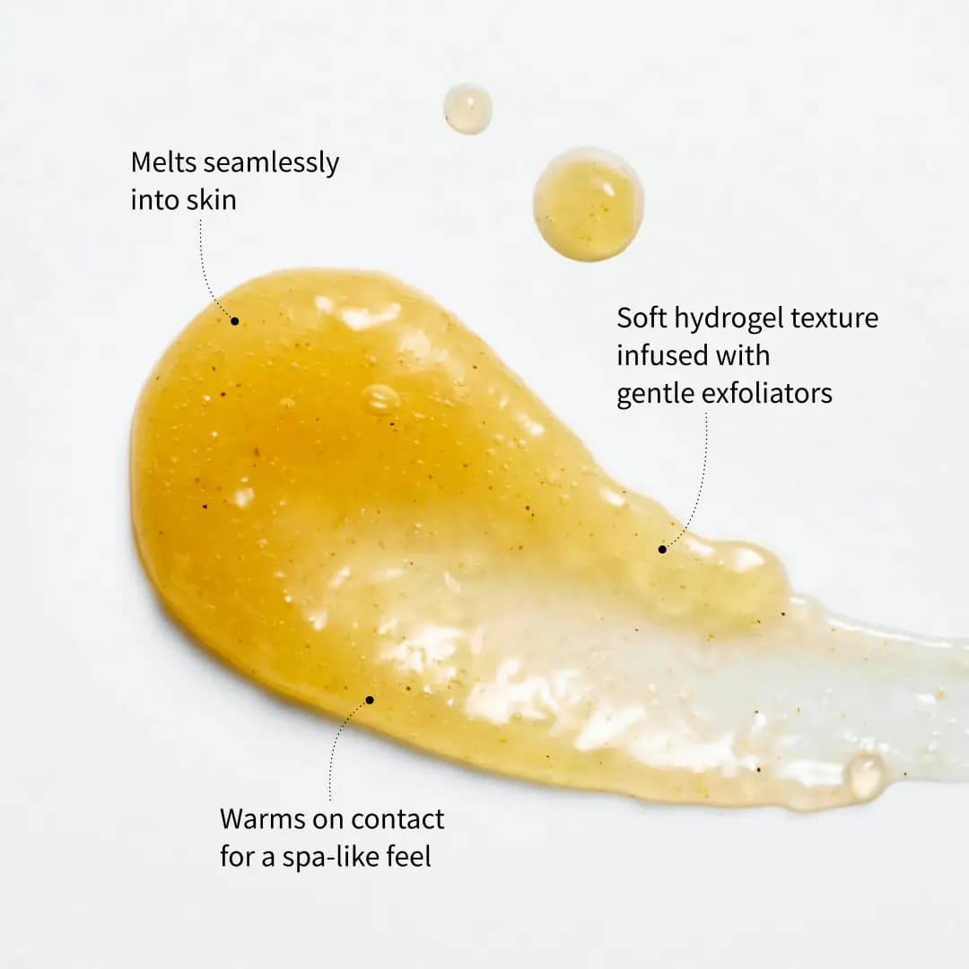 Swatch of golden amber hydrogel with fine exfoliating flecks and droplets, labelled as warming and melting into skin